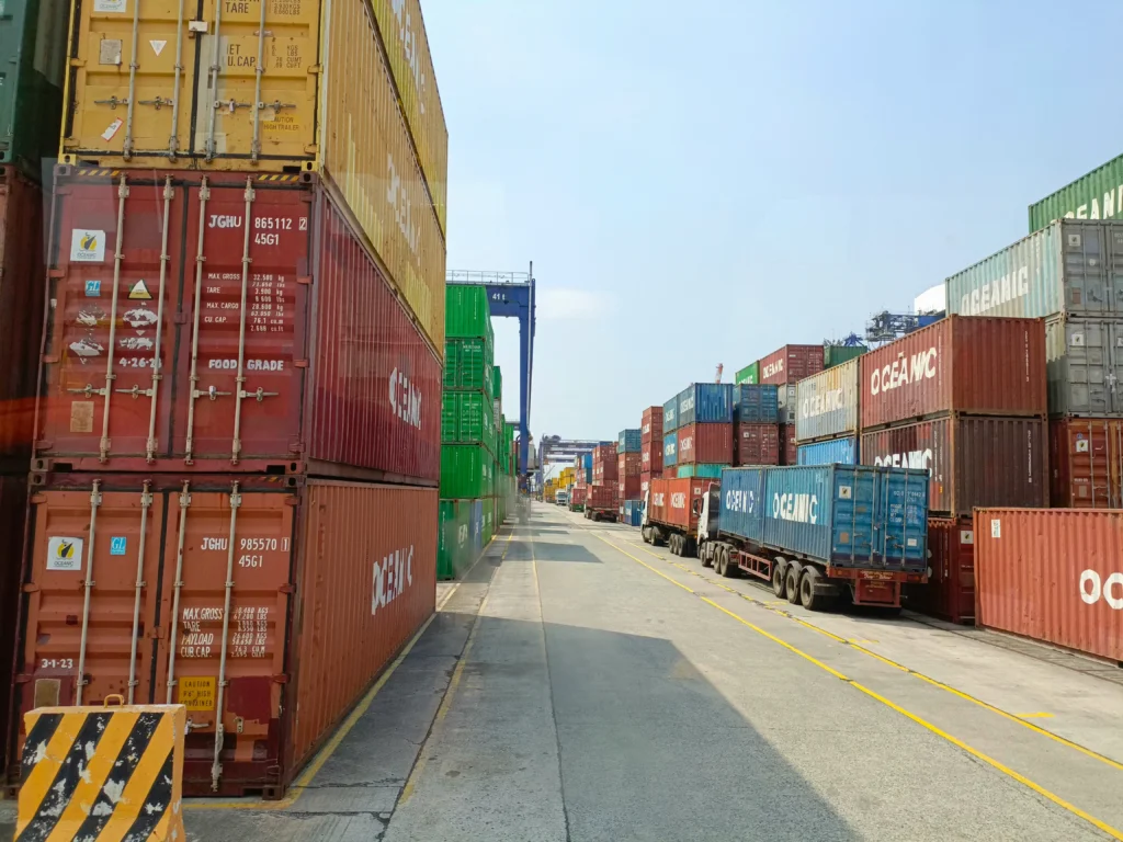 Shipping containers and trucks at a busy seaport, showing international logistics.